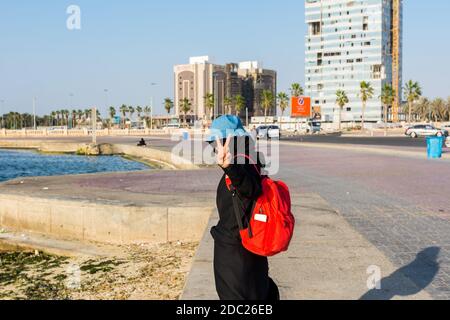 Una turista femminile con zaino rosso che indossa hijab in Jeddah Corniche, 30 km località costiera della città di Jeddah, Arabia Saudita Foto Stock
