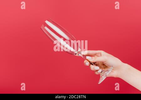 vista ritagliata di una donna che tiene vuoto bicchiere di champagne isolato sopra rosso Foto Stock