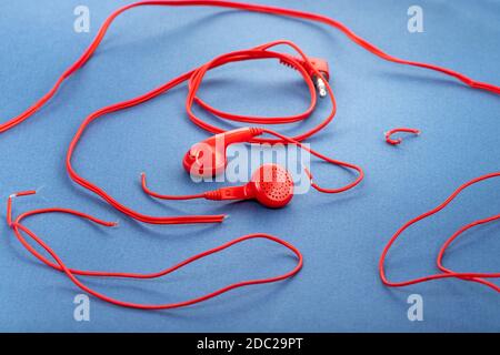 Cuffie su sfondo blu. Cuffie strappate. Riparazione dei dispositivi elettronici. Filo rotto. Foto Stock