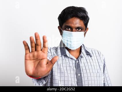 Closeup Asian bel uomo nero indossando chirurgico igienico maschera di protezione contro il coronavirus e sollevare il segno di arresto mano, studio colpo isolo Foto Stock