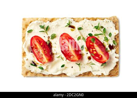 Croccanti di pane con formaggio cremoso, fette di pomodoro ed erbe su bianco Foto Stock