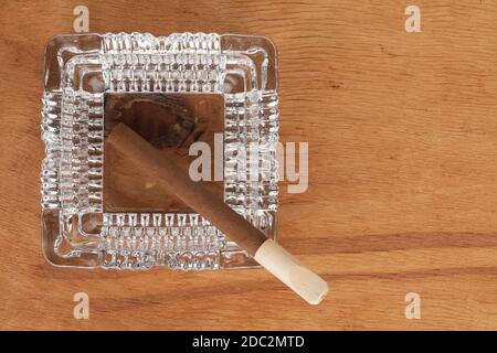 Posacenere in vetro con cavalletti per sigari su una superficie in legno, può essere utilizzato come sfondo Foto Stock