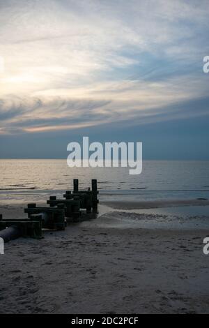 Un tubo grande con poli di legno su ogni lato che si attacca Fuori nell'oceano Foto Stock