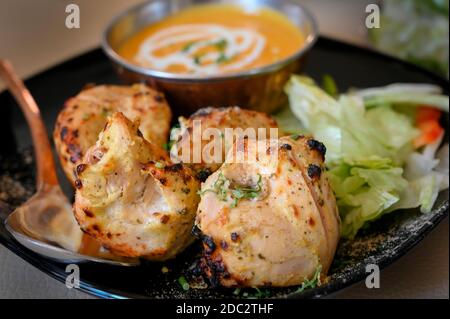 Pezzi di pollo marinati davanti a una ciotola di salsa di curry in un ristorante indiano in Inghilterra. Foto Stock