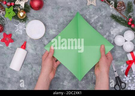 Artigianato di Natale - albero di Natale fatto di carta colorata, passo dopo passo istruzioni. Punto 7- ottenga un quadrato con le pieghe lungo due diagonali Foto Stock