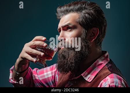 Il barista uomo con la barba trattiene il brandy di vetro. Il sommelier ha un gusto alcolico costoso. Foto Stock