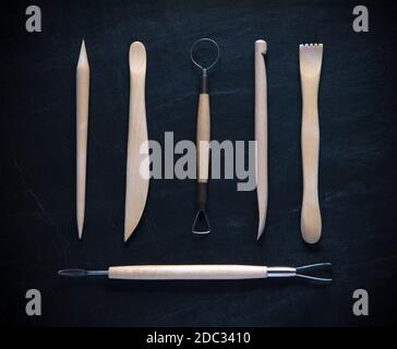gruppo di utensili di ceramica per la lavorazione di argilla a maglia piatta design shot per lo sfondo del testo dall'alto con ardesia scura Foto Stock