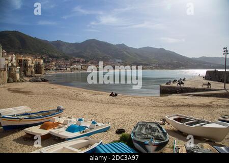 Céfalu, Sicilia, Italia - 16 Marzo 2018: una rilassante giornata di sole sulla spiaggia di Céfalu, con poche persone irriconoscibili e vecchi edifici tipici Foto Stock