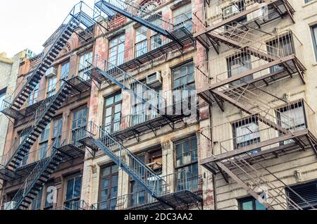 Vista ad angolo basso di edifici di appartamenti tipici con scale di fuga dal fuoco a Manhattan, New York City, Stati Uniti Foto Stock