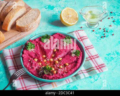 Hummus rosso tradizionale in un piatto su un tavolo blu. Foto Stock