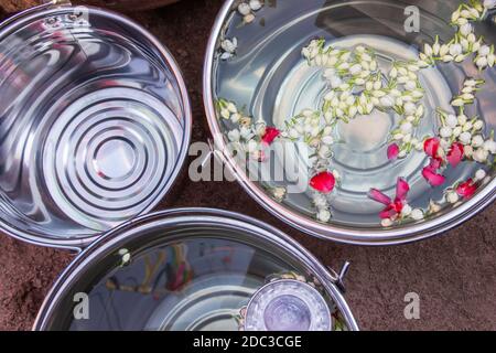 Gelsomini e petali di rosa galleggiano in un grande secchio di acciaio inossidabile per il festival di songkran in thailandia. Foto Stock