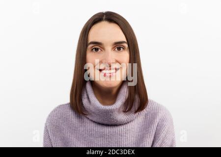 Primo piano seducente donna bruna sorridente in un pullover viola che attende con impazienza un evento emozionante, grinning esprime gioiosamente positività Foto Stock