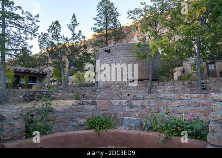 Gli edifici moderni costruiti in stile Pueblo servono come un Centro visitatori e negozio di articoli da regalo nel monumento nazionale di Bandelier con alte pareti erose in pietra arenaria Foto Stock