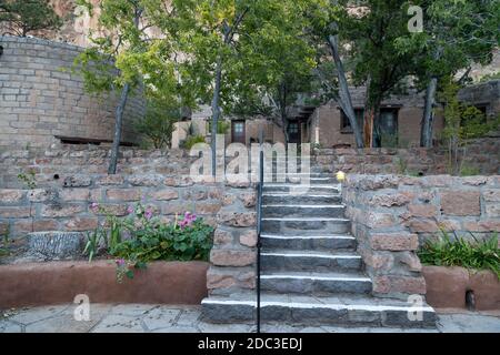 Gli edifici moderni costruiti in stile Pueblo servono come un Centro visitatori e negozio di articoli da regalo nel monumento nazionale di Bandelier con alte pareti erose in pietra arenaria Foto Stock