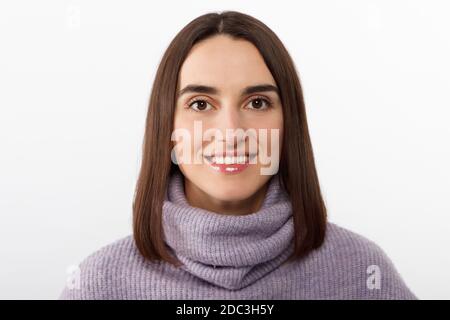 Primo piano seducente donna bruna sorridente in un pullover viola che attende con impazienza un evento emozionante, grinning esprime gioiosamente positività Foto Stock