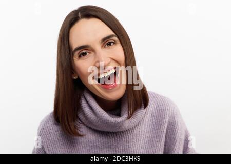 Studio shot di sorridente donna felice ha un aspetto accattivante, sorride ampiamente, posa su sfondo bianco esprime emozioni positive come Foto Stock