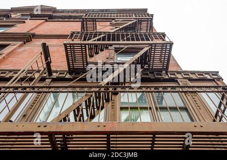 Vista ad angolo basso dei tipici appartamenti di New York City con scale di fuga dal fuoco a Manhattan, New York, Stati Uniti Foto Stock
