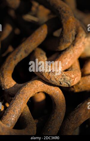 Primo piano Macro dei link di UN pile di vecchia, ferro Rusty Chain illuminato dal Sole. Foto Stock