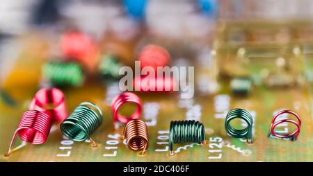 Induttori elettromagnetici a nucleo d'aria per alte frequenze su sfondo panoramico della scheda a circuito stampato. Bobine elettroniche all'interno del dispositivo TV che ricevono il segnale RF. Foto Stock