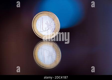 una moneta in euro riflessa su uno sfondo colorato Foto Stock