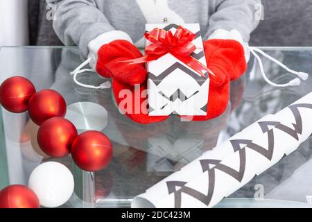 Una ragazza in un maglione grigio con un coniglio tiene un regalo di Natale con i mittenti rossi nelle sue mani. Capodanno, Natale, vacanze invernali, palle di Natale, regalo Foto Stock