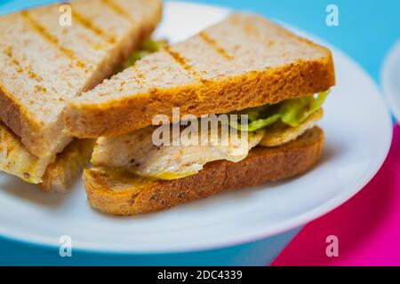 Club sandwich con carne di pollo alla griglia servita su piatto bianco Nel cafe. Deliziosi spuntini nel ristorante fast food Foto Stock