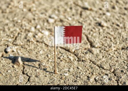 Una vista della bandiera nazionale del Qatar su una terra desertica. Foto Stock