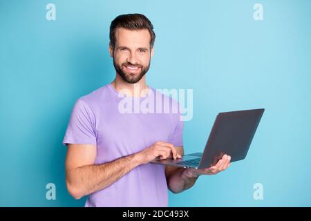 Ritratto fotografico di sorridente millenario che tiene il computer studiare la navigazione in Internet sfondo isolato di colore blu intenso Foto Stock