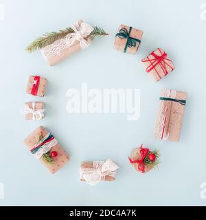 Composizione regalo del cerchio di Natale. Corona di abete, bacche di mirtillo e confetti bianchi su sfondo blu. Design semplice. Disposizione piatta Foto Stock