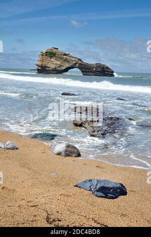 Onde, rocce su una spiaggia di sabbia e un'isola con un buco. Arco in pietra naturale. Oceano acqua. Costa atlantica nella Francia sud-occidentale. Estate soleggiato giorno con b Foto Stock