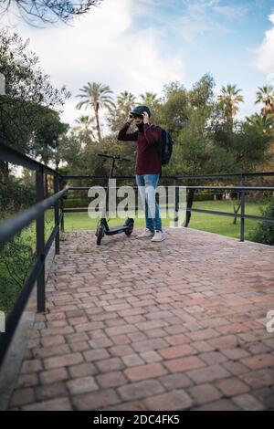 Ragazzo mettendo il casco sul suo scooter elettrico prima di andare a lavorare. Foto Stock