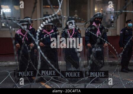 Durante la dimostrazione, i poliziotti della polizia riota si trovano in guardia dietro la recinzione di filo spinato all'interno della Royal Thai Police Headquarter. I manifestanti pro-democrazia si sono riuniti all'incrocio di Ratchaprasong e hanno marciato verso la sede della Royal Thai Police per spruzzare colore e acqua a seguito di una rivolta di polizia utilizzando gas lacrimogeni e cannoni ad alta pressione per prevenire i manifestanti Di avvicinarsi al Congresso durante il dibattito costituzionale. Foto Stock