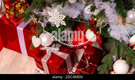 Regali avvolti sotto l'albero di Natale. Molte scatole di regali sul pavimento vicino all'albero di conifere. Concetto di vacanze e sorprese Foto Stock