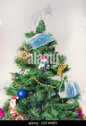 albero di natale concettuale decorato con maschere corona virus 2020 mondo pandemia Foto Stock