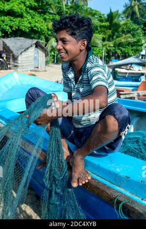 Un pescatore che sbatte le sue reti sulla spiaggia di Arugam Bay dopo essere tornato dalla pesca la notte precedente. Arugam Bay si trova sulla costa orientale dello Sri Lanka. Foto Stock