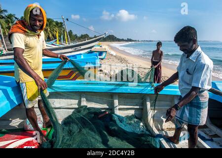 I pescatori sbattono le reti sulla spiaggia di Arugam Bay dopo essere tornati dalla pesca la notte precedente. Arugam Bay si trova sulla costa orientale dello Sri Lanka. Foto Stock