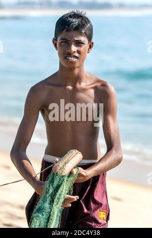 Un pescatore che sbatte le sue reti sulla spiaggia di Arugam Bay dopo essere tornato dalla pesca la notte precedente. Arugam Bay si trova sulla costa orientale dello Sri Lanka. Foto Stock