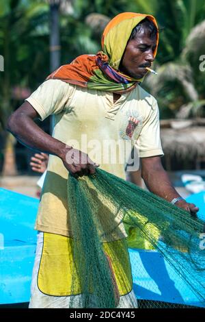 Un pescatore che sbatte le sue reti sulla spiaggia di Arugam Bay dopo essere tornato dalla pesca la notte precedente. Arugam Bay si trova sulla costa orientale dello Sri Lanka. Foto Stock