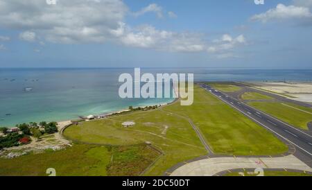 Pista all'aeroporto internazionale Denpasar di Bali, Indonesia. Pista che raggiunge l'oceano. Vista aerea dell'aeroporto di Ngurah Rai Foto Stock