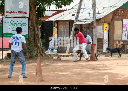 Uomini che giocano a cricket su un campo sterrato in strada a Sigiriya in Sri Lanka. Cricket è uno degli sport più popolari in Sri Lanka. Foto Stock