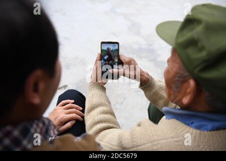 (201119) -- XIANGXI, 19 novembre 2020 (Xinhua) -- Peng Guofei (L) mostra i suoi brevi video per il villager Peng Hongyun al villaggio di Yangmu di Furong Township a Xiangxi Tujia e Prefettura Autonoma di Miao, Provincia di Hunan della Cina centrale, 15 novembre 2020. Peng Guofei, 75, è noto come 'nonno Fei' online. È nato e cresciuto nel remoto villaggio di Yangmu, situato nel profondo delle montagne di Wuling. Con l'aiuto di funzionari locali di soccorso alla povertà, gli abitanti del villaggio hanno accesso a Internet negli ultimi anni, come l'intero villaggio abbraccia la copertura completa del segnale 4G. All'inizio del 2020, Peng ha preso corsi su internet Foto Stock