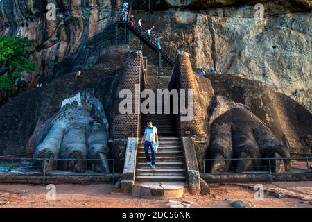 Un uomo cammina attraverso i Lions Paws che conduce alla cima del Sigiriya Rock, Sri Lanka. Le zampe sono tutto ciò che rimane di una magnifica statua di leone. Foto Stock