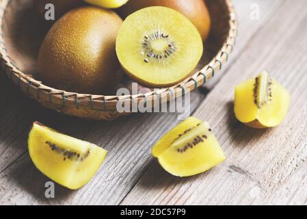 Fetta di Kiwi sul cesto, primo piano di frutta gialla kiwi su sfondo di legno Foto Stock