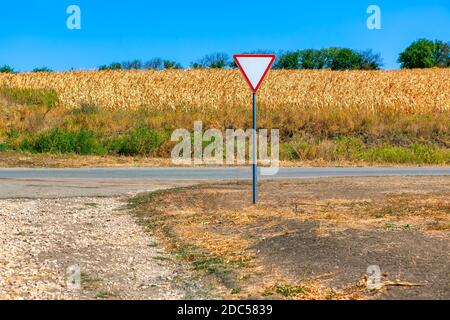 Strada di campagna e campo agricolo . Segnale stradale dare modo Foto Stock