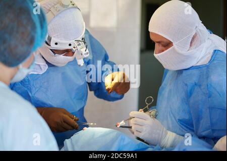 Chirurgia. Squadra di chirurghi in tute blu cucire la ferita. Foto Stock