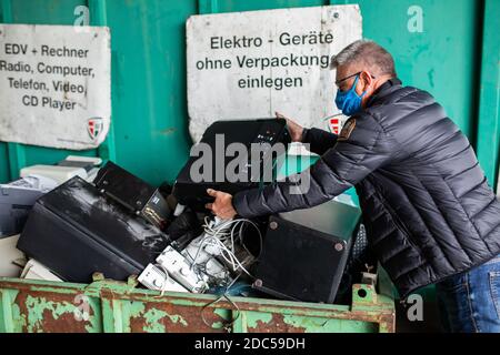 Friburgo, Germania. 13 Nov 2020. Un uomo mette una stampante in un contenitore per lo smaltimento nei locali del cantiere di riciclaggio St. Gabriel della società di gestione dei rifiuti e di pulizia delle città ASF della città di Friburgo. L'attuale blocco dovuto alla pandemia della corona sta causando una forte corsa ai cantieri di riciclaggio e di materiali riutilizzabili delle aziende municipali di smaltimento dei rifiuti. Molti cittadini usano il tempo che si è guadagnato a casa per risolvere i rifiuti superflui. Credit: Philippe von Ditfurth/dpa/Alamy Live News Foto Stock