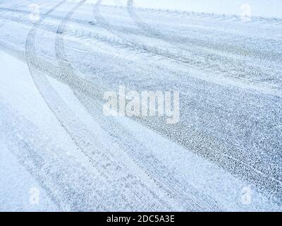 fondo stradale asfaltato nevoso con attraversamento di impronte di pneumatici Foto Stock