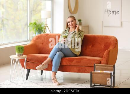 Giovane donna che beve succo di erba del siero a casa Foto Stock