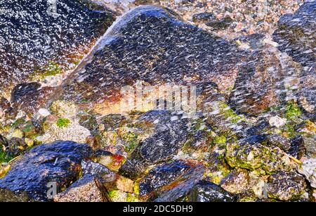 Splendore e magia degli spruzzi d'acqua sullo sfondo di pietre multicolore Foto Stock