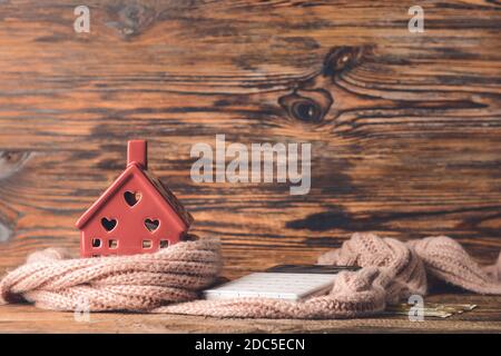 Figura di casa, calcolatrice, soldi e sciarpa calda sul tavolo. Concetto di stagione di riscaldamento Foto Stock